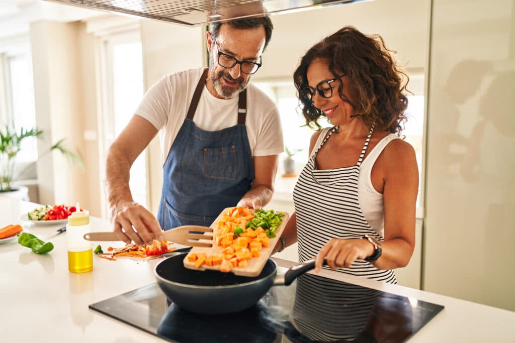 Middle age hispanic couple Smiling confident pouring food on frying